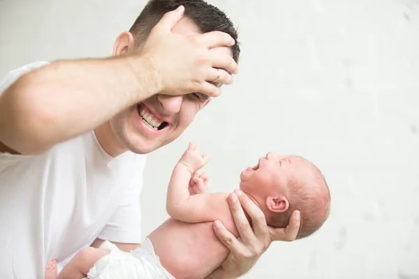 Un uomo che tiene un neonato urlante, con la mano alla testa — Foto Stock