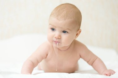 Cute baby raises head and chest, burping after eating clipart