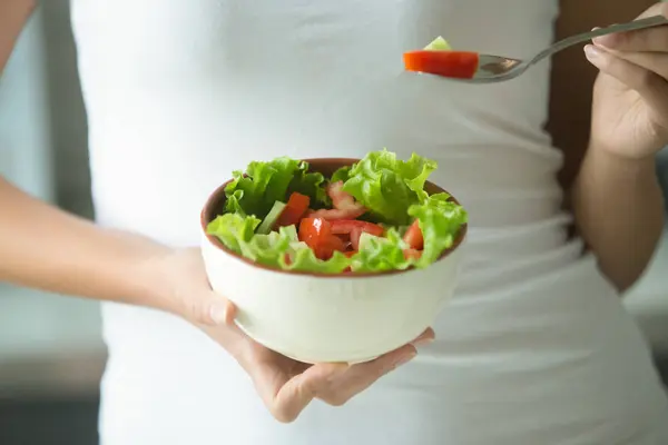 Vrouwelijke handen met een kom met groene salade — Stockfoto