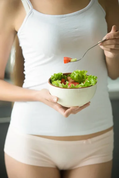 Vrouw in ondergoed houdt een kom met groene salade — Stockfoto