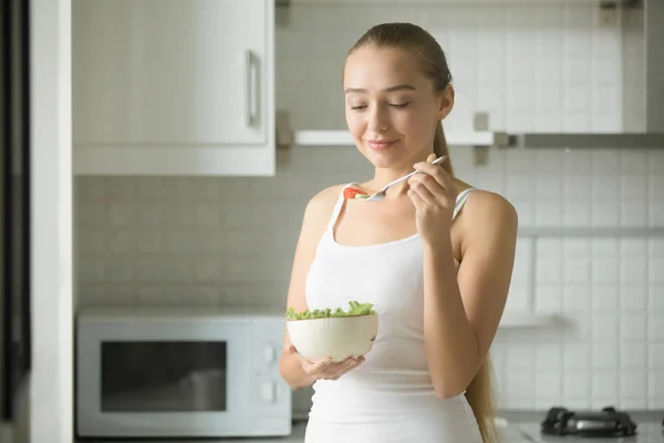 Портрет привлекательной женщины, пробующей свежий салат на кухне — стоковое фото