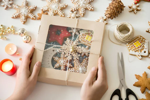 Fechar as mãos segurando uma caixa festiva com biscoitos de Natal — Fotografia de Stock