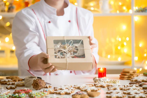 Mãos de confeiteiro mostrando uma caixa com biscoitos de gengibre — Fotografia de Stock