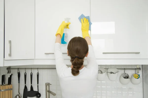 Вид сзади на молодую женщину, убирающую белый кухонный шкаф — стоковое фото