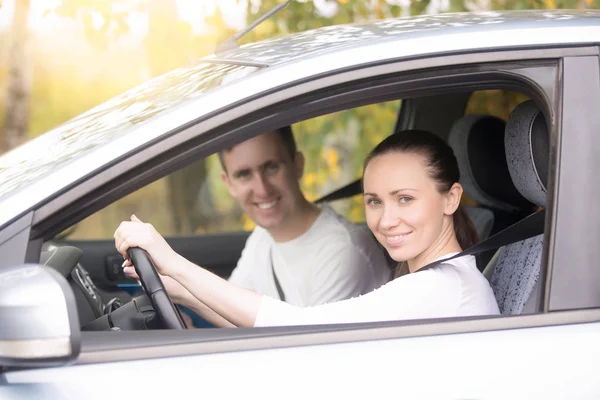 Young woman driving, a man sitting near in the car — Stock Photo, Image