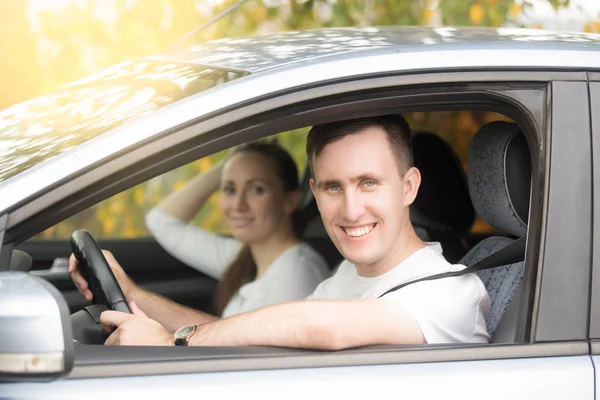 Young smiling man driving and woman sitting in the car — Stock Photo, Image