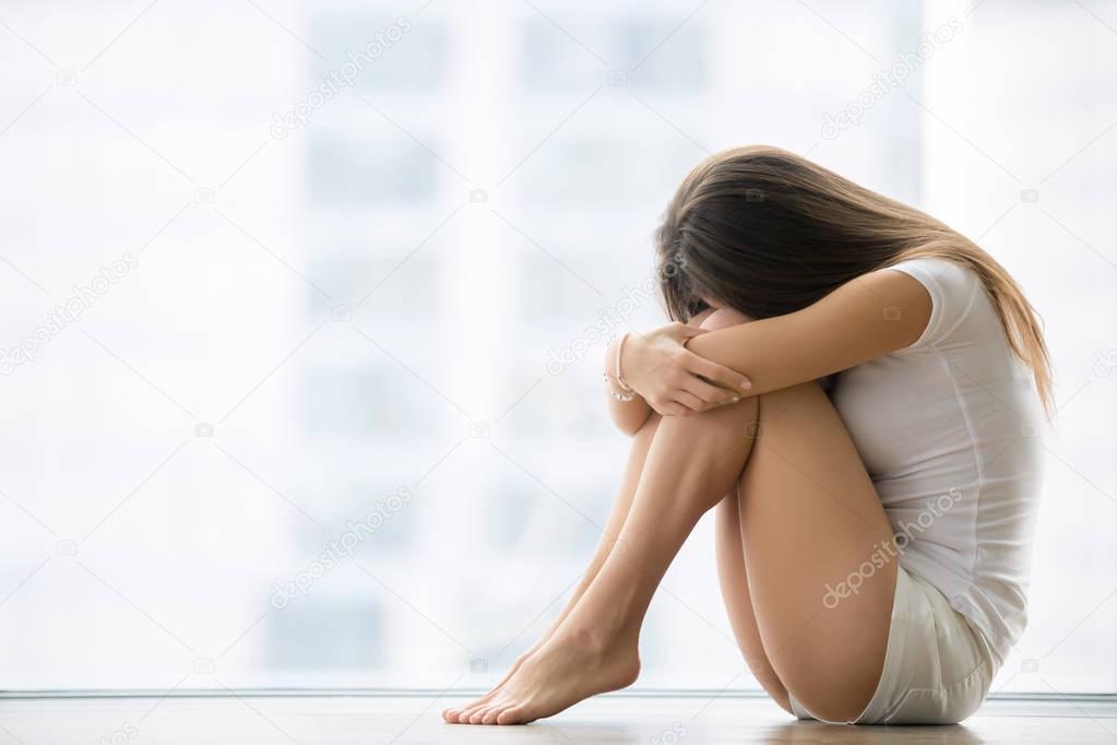 Young woman sitting near the window her head down