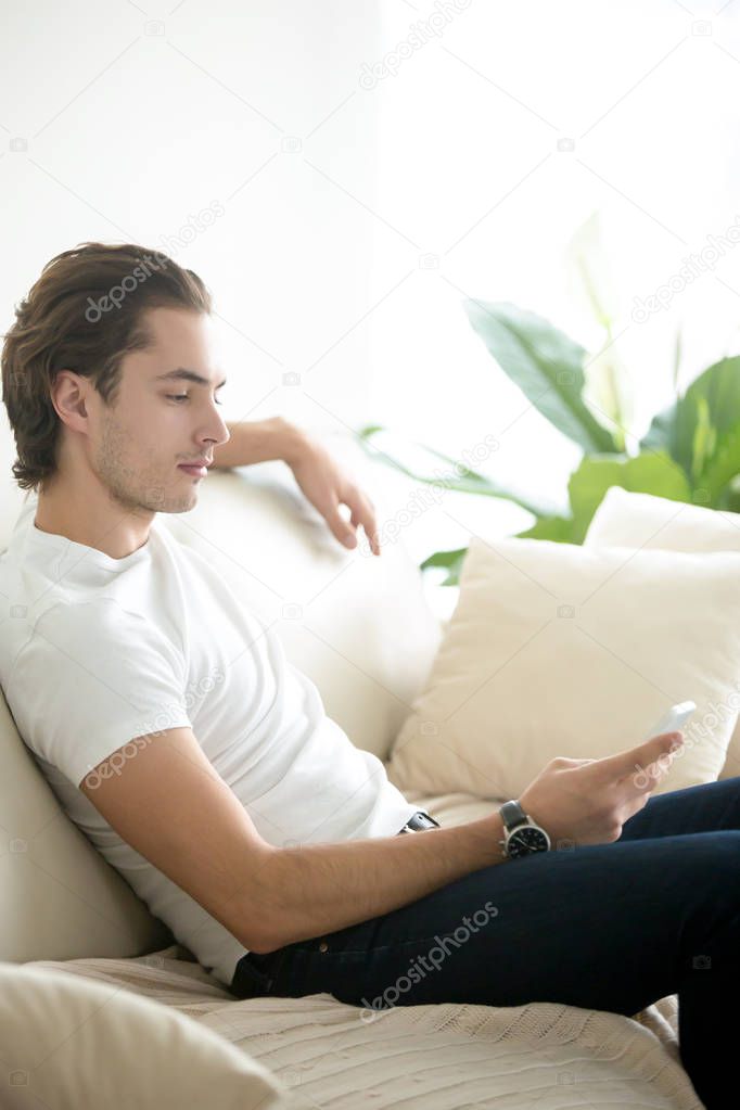 Young handsome man sitting relaxed with phone