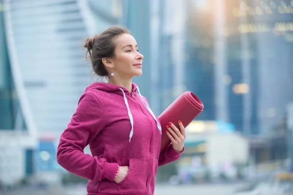 Joven mujer deportiva sosteniendo esterilla de yoga —  Fotos de Stock