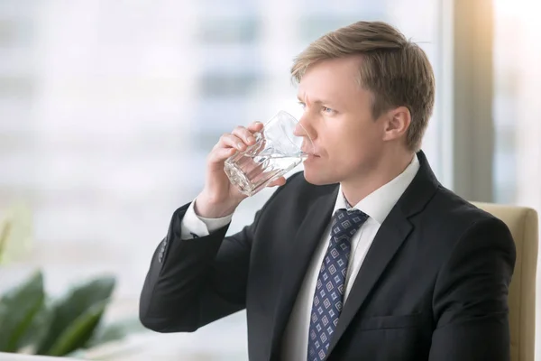 Uomo d'affari che beve acqua alla scrivania — Foto Stock