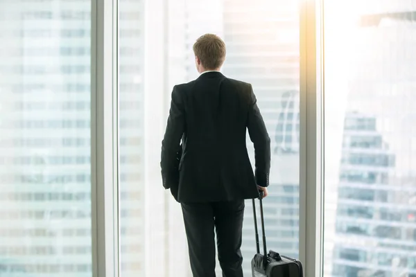 Бізнесмен стоїть з валізою біля вікна — стокове фото