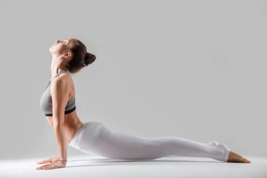 Genç kadın Urdhva mukha shvanasana poz, gri studio backgro