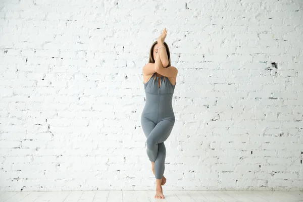 Genç çekici kadın Garudasana poz, beyaz stüdyo backgrou