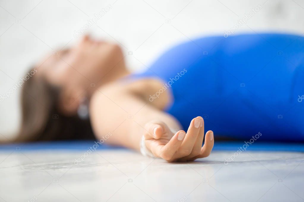 Young attractive woman in Corpse pose, white studio background