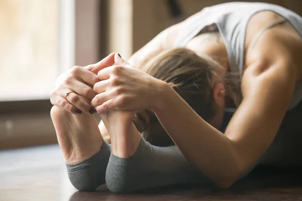 Paschimottanasana の若い女性のポーズ、ホーム インテリアの背景, — ストック写真