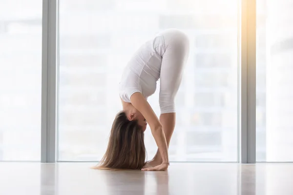 Junge attraktive Frau posiert in uttanasana gegen Bodenfenster — Stockfoto