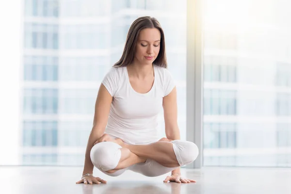 Junge attraktive Frau in Tolasana posiert gegen Bodenfenster — Stockfoto