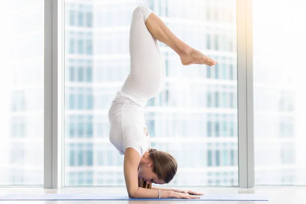 Mujer joven en Pincha Mayurasana, cerca de la ventana del piso — Foto de Stock