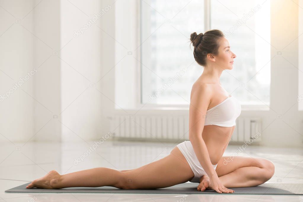 Young woman in One Legged King Pigeon pose, white background