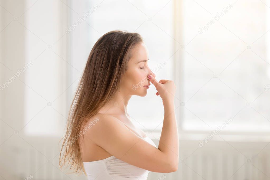 Young attractive woman making Alternate Nostril Breathing, white