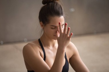 Genç çekici kadın yapma nadi shodhana pranayama, gri stud