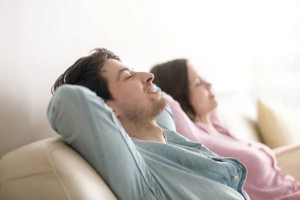 Hombre joven y mujer relajante, ojos cerrados, vista lateral, interior — Foto de Stock