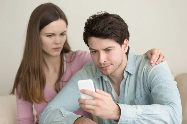 Jeune homme utilisant un smartphone, ayant des problèmes, petite amie anxieuse — Photo