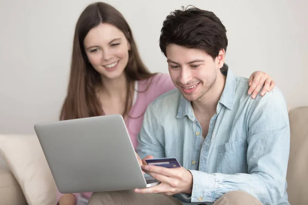 Young happy couple shopping online via laptop with credit card — Stock Photo, Image