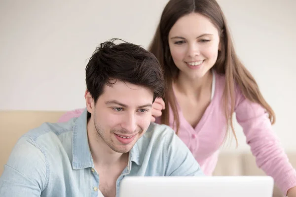 Young smiling man and woman using laptop computer indoors — Stock Photo, Image