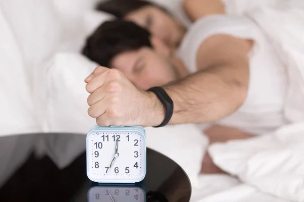 Couple waking up early, guy turning off annoying alarm clock — Stock Photo, Image