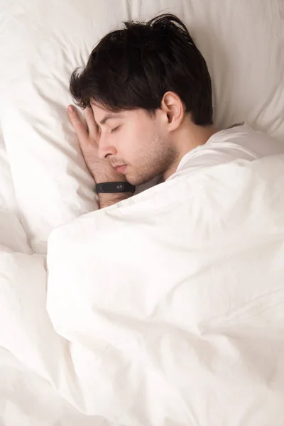 Anak muda tidur di tempat tidur memakai jam tangan pintar, tidur pelacak — Stok Foto