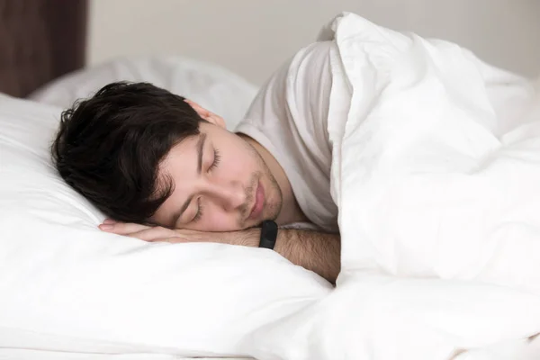 Красивий чоловік спить у ліжку в наручнику для відстеження сну — стокове фото