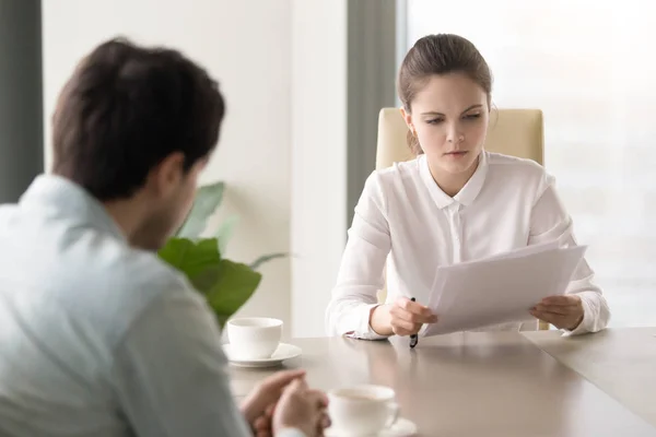 Serious businesswoman studying papers sitting opposite man at of — Stock Photo, Image