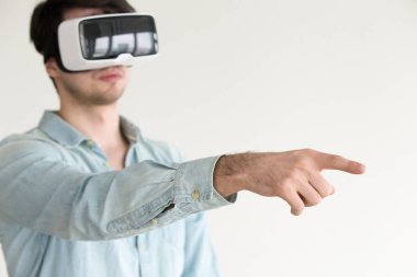 Genç adam giyen vr kask gösteren veya sanal nesneleri dokunmadan