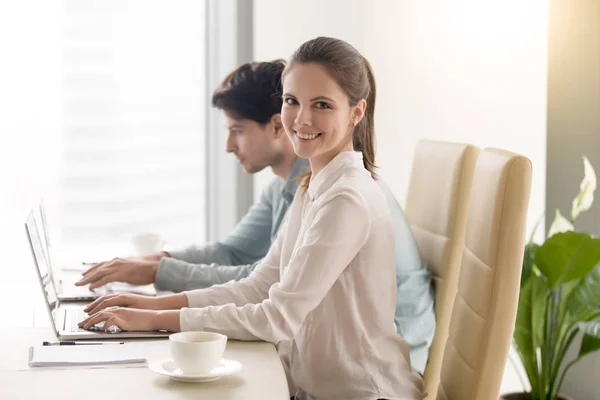 Happy young businesswoman looking at camera, working with male c — Stock Photo, Image