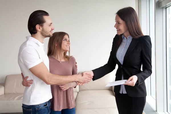 Couple souriant serrant la main d'un agent immobilier lors d'une réunion intérieure — Photo