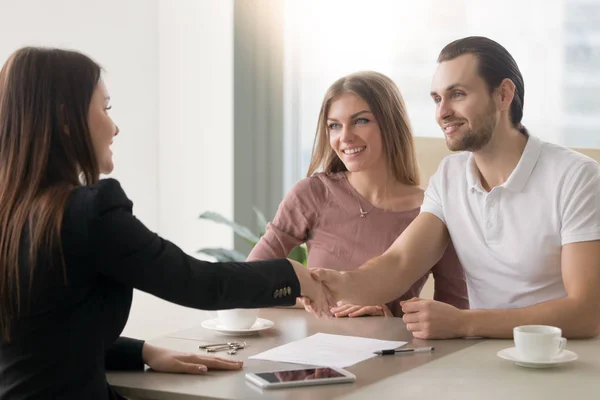 Jonge familie paar ontmoeting met makelaar, handdruk symboliseert een — Stockfoto