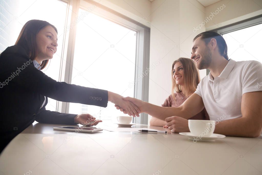 Couple and realtor handshaking over the table, real estate deal