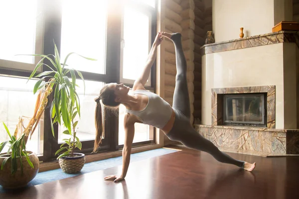 Jonge yogi vrouw in zijkant Plank poseren, home interieur achtergrond — Stockfoto