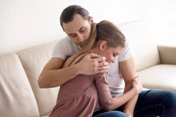 Retrato de pareja feliz joven abrazándose sentado en el sofá en el interior — Foto de Stock