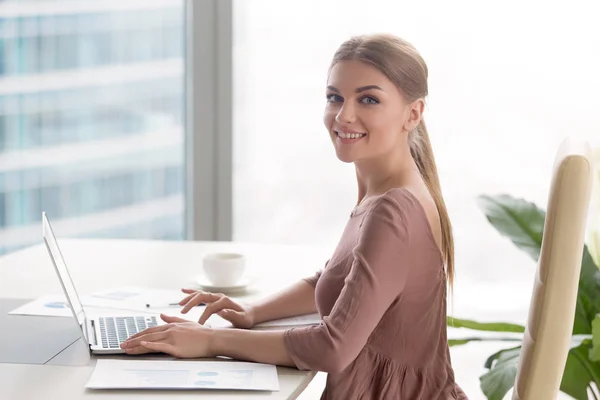 Junge lächelnde Geschäftsfrau sitzt am Schreibtisch und schaut auf ca. — Stockfoto