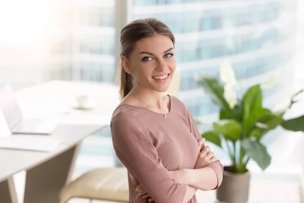 Happy young businesswoman standing with arms crossed, smiling at — Stock Photo, Image