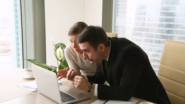 Young excited colleagues looking at laptop, hugging and celebrating victory — Stock Video