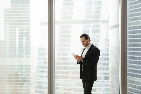 Empresario trabajando en tableta cerca de ventana grande — Foto de Stock