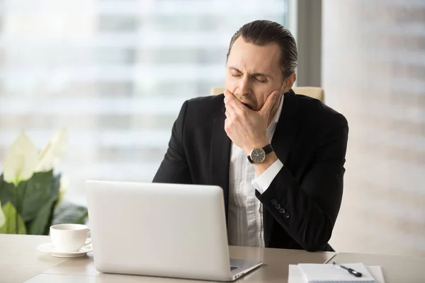 Businessman struggling with drowsiness at work