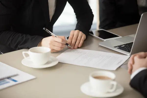 Main féminine va signer le document, mettre la signature, fermer — Photo