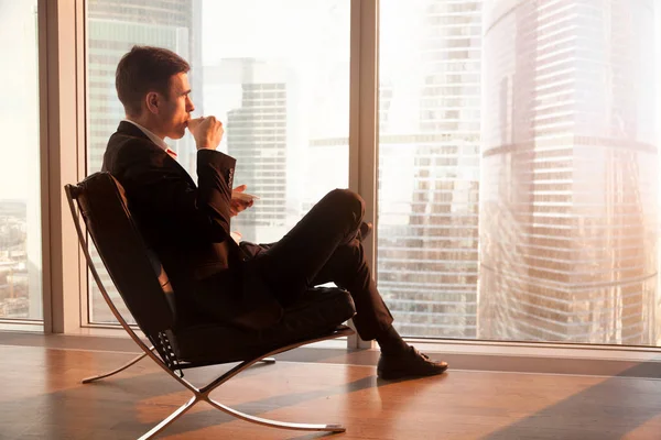 Businessman sitting in office chair enjoying coffee in the morni