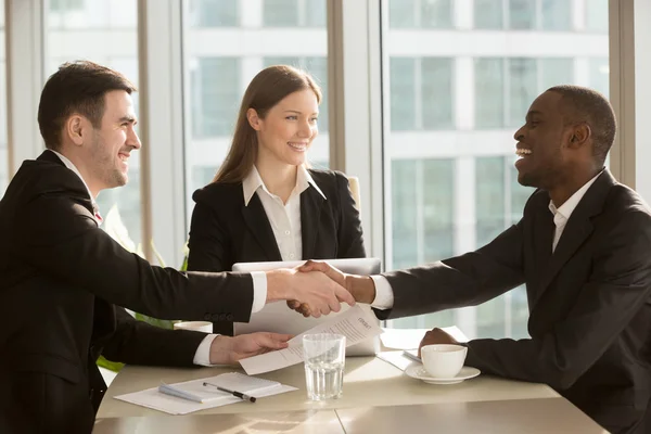 Happy smiling black and white businessmen handshaking after sign