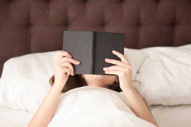 Bayan rahatlatıcı en sevdiği kitap ile rahat yatakta