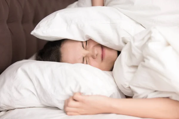 Woman covering head with pillow because of noise — Stock Photo, Image